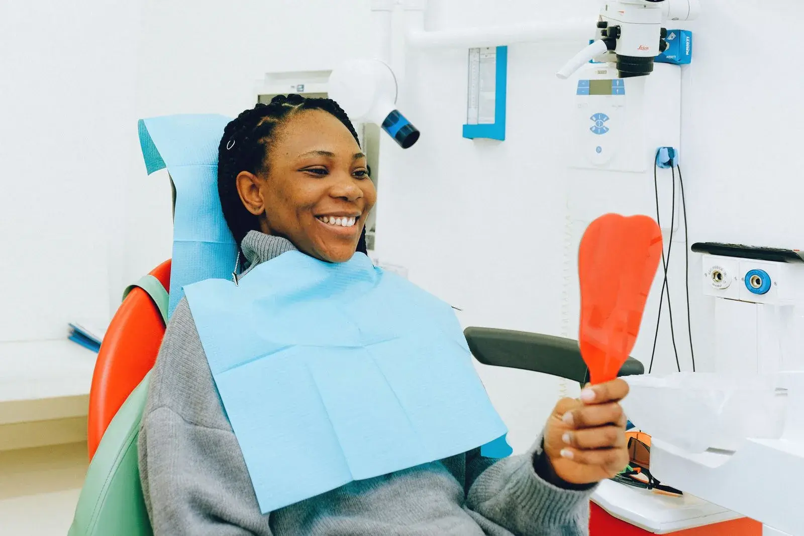 Paciente sorrindo com espelho na consulta do plano odontológico Bradesco Dental