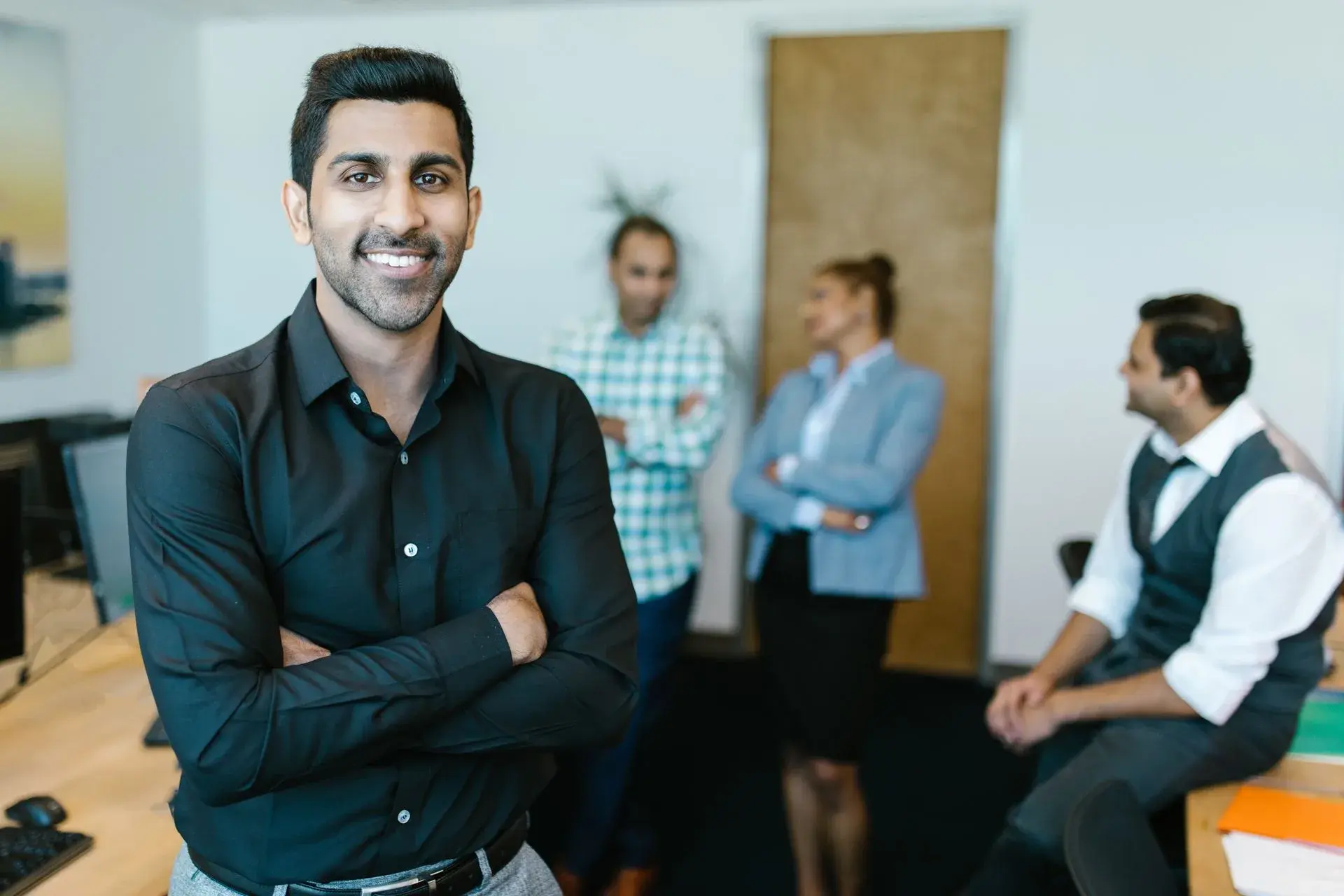 Profissional sorridente no escritório com a equipe, empresa com Bradesco Saúde Ideal