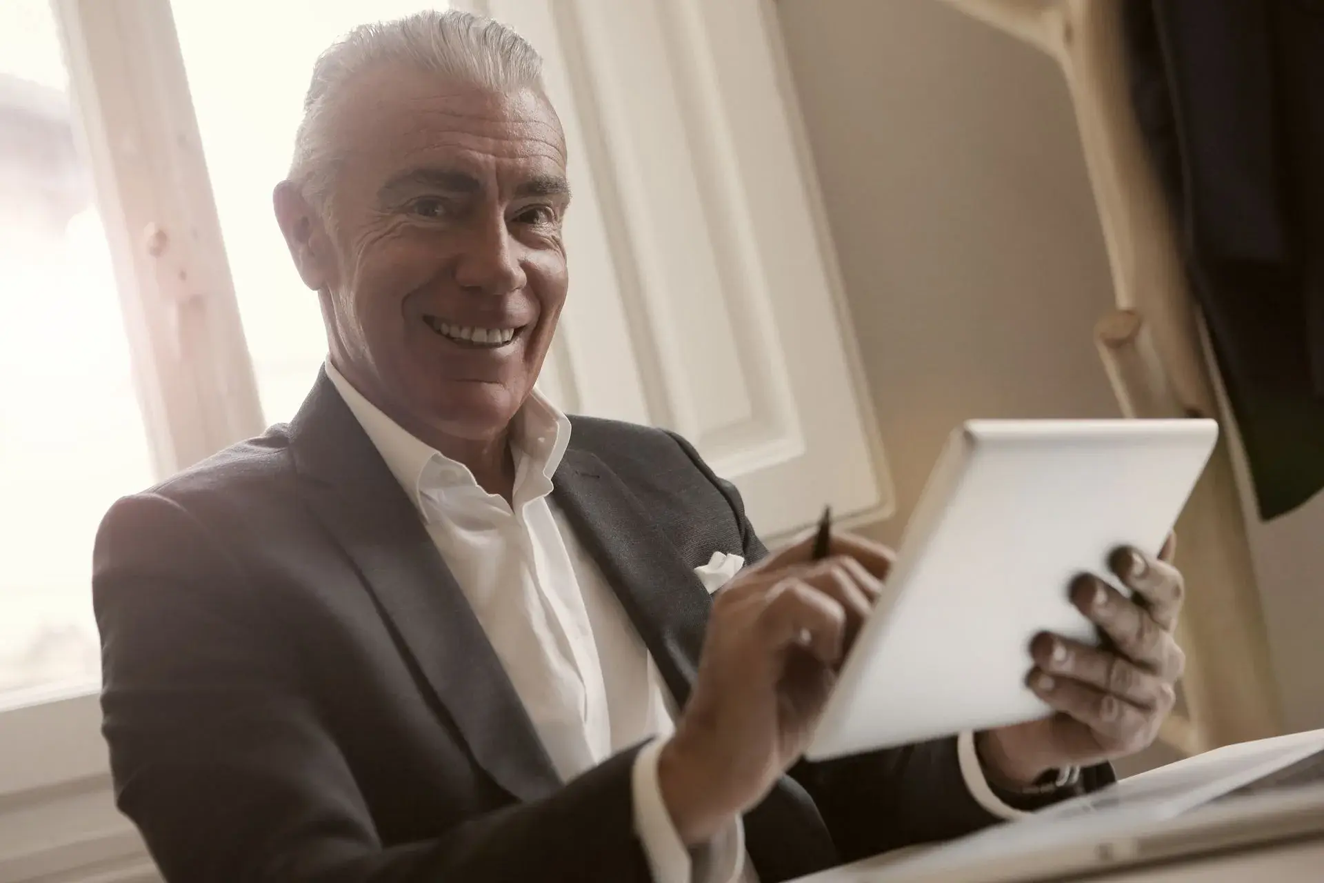 Executivo sorrindo com tablet no escritório, beneficiário do plano Bradesco Saúde Premium