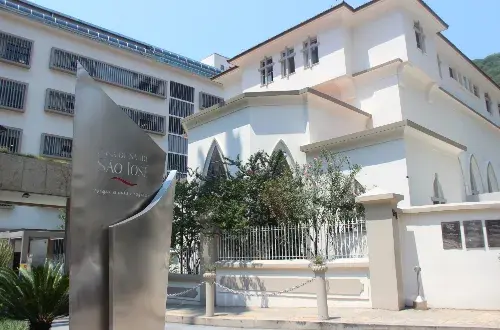 Prédio histórico branco da Casa de Saúde São José, com o totem na entrada