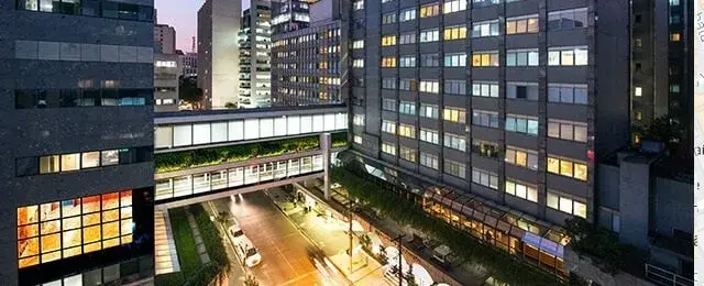 Prédios do HCor à noite, ligados por passarela, na Rua Abílio Soares