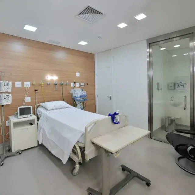 Quarto da Pro Matre Paulista com monitor, poltrona e banheiro de vidro