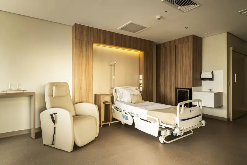 Suíte de internação do Hospital Vila Nova Star, com poltrona e madeira clara