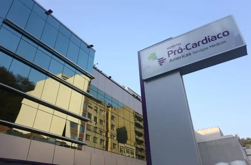 Totem com o nome do Hospital Pró-Cardíaco diante do prédio de vidro